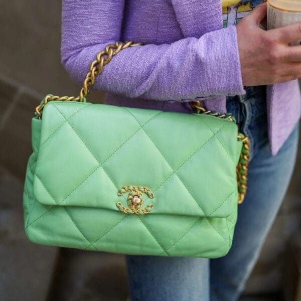 A person in a light purple blazer and blue jeans holds a light green quilted Chanel handbag, highlighting the expert personal styling of Style Reclaimed: Your Transformation Experience.